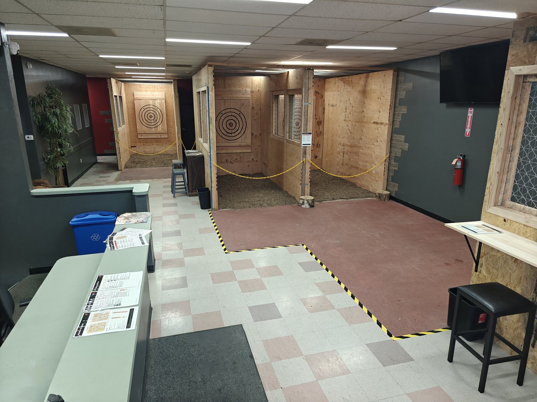 Four indoor axe throwing lanes at Chopscape in Oceanside, each with a wooden target board and a marked throwing line
