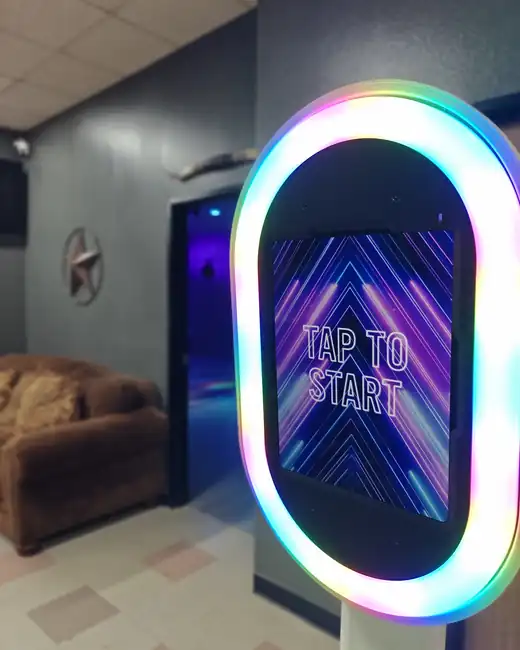 The Chopscape photobooth kiosk with its colour-changing ring light, showing a Tap to Start screen, in the lounge outside the party room