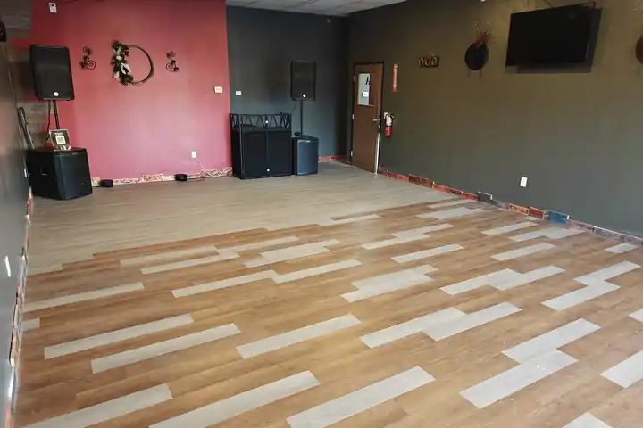 The far end of the party room showing the DJ booth, two PA speakers on stands and a red accent wall